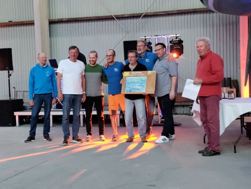 Von links. Die Crew: Mathias Grundschöttel, Felix Bartel, Julian de Mos, Ulli Zimmer, Heiko Heese (Skipper und Regattaleiter), Pascal Schmitz. Eingerahmt von Karlo Schmiedel (Vize-Sport HSeV, links) Klaus Dieter Lachmann (Präsident des HSeV und Wettfahrtleiter, rechts)    Bild: Heiko Heese