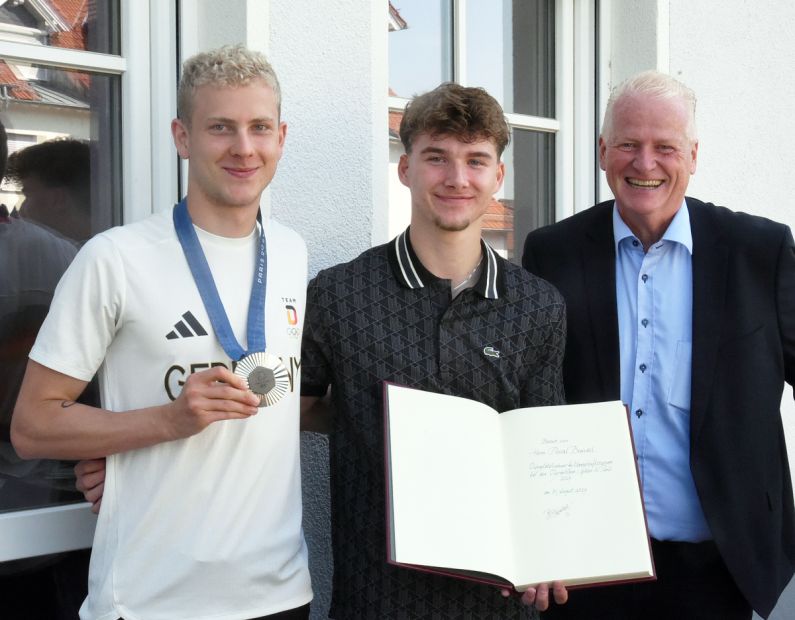 Die Olympia-Teilnehmer Oliver Klemet (links) und Pascal Brendel (Mitte) haben sich zur Freude von Wehrheims Bürgermeister Gregor Sommer in das „Goldene Buch“ der Gemeinde eingetragen.
Foto: Gerhard Strohmann